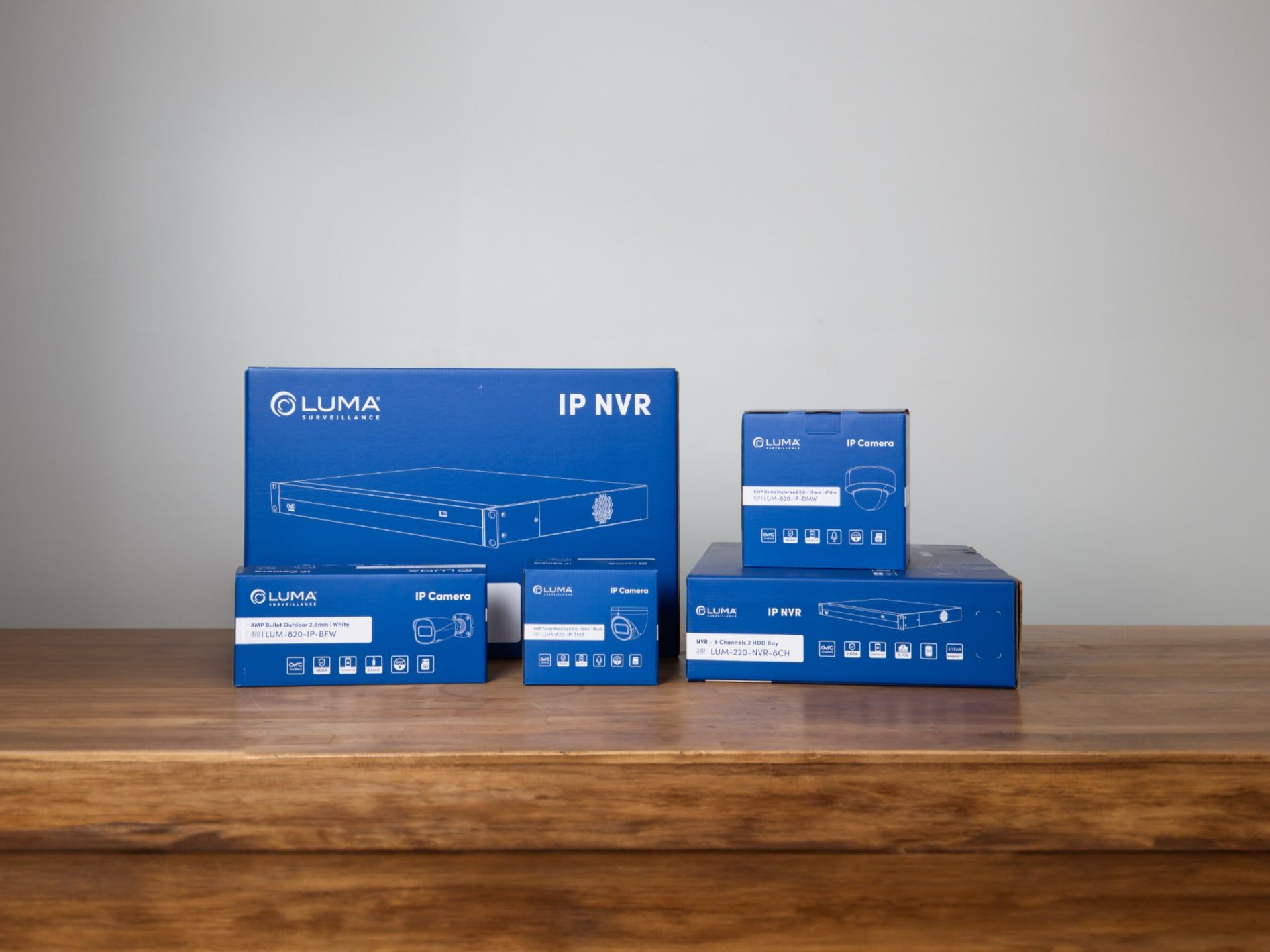 Blue Luma IP NVR box with smaller camera boxes on a wooden shelf