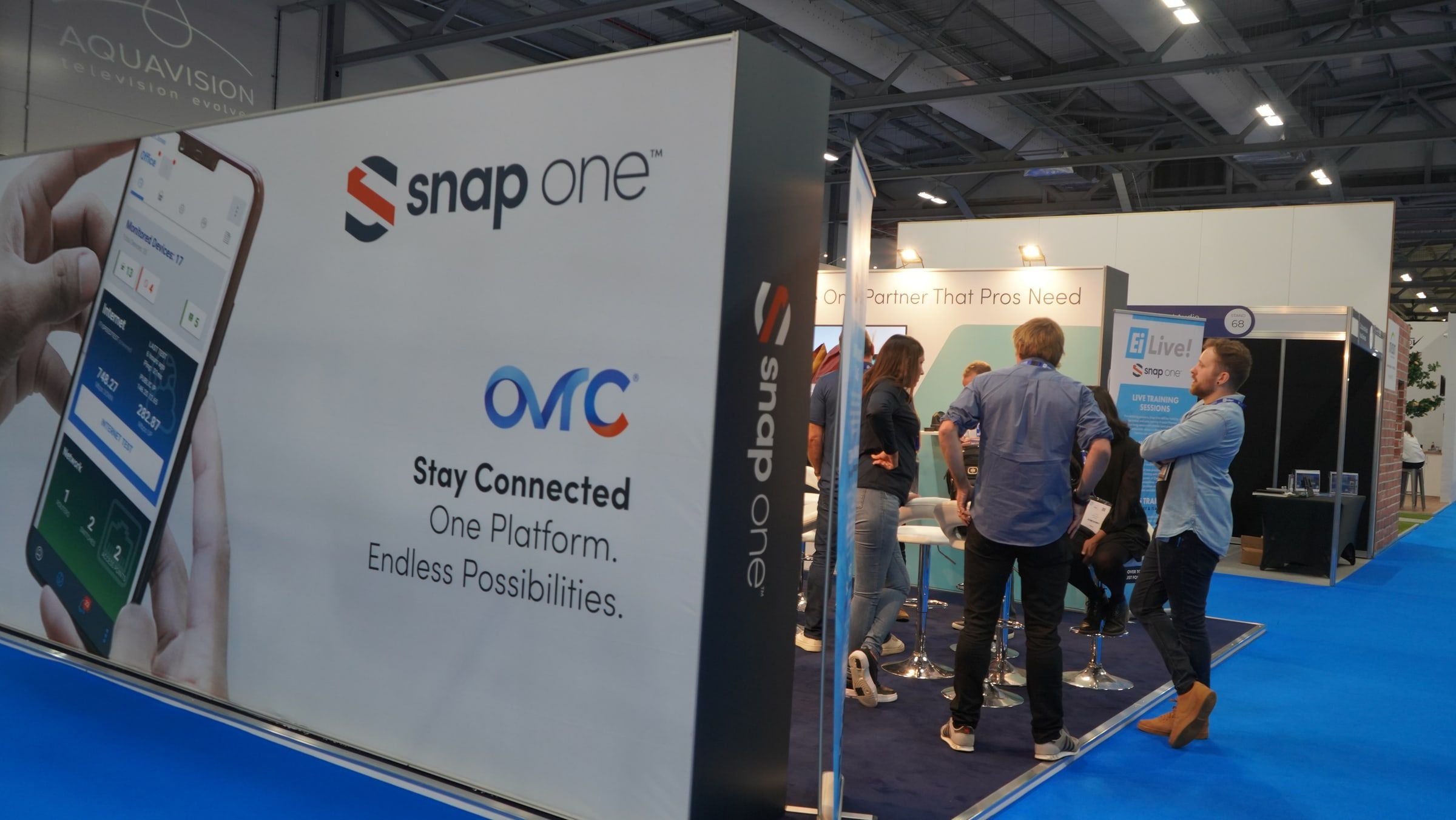 Snap One trade show booth wall showing the new logo and an OvrC display